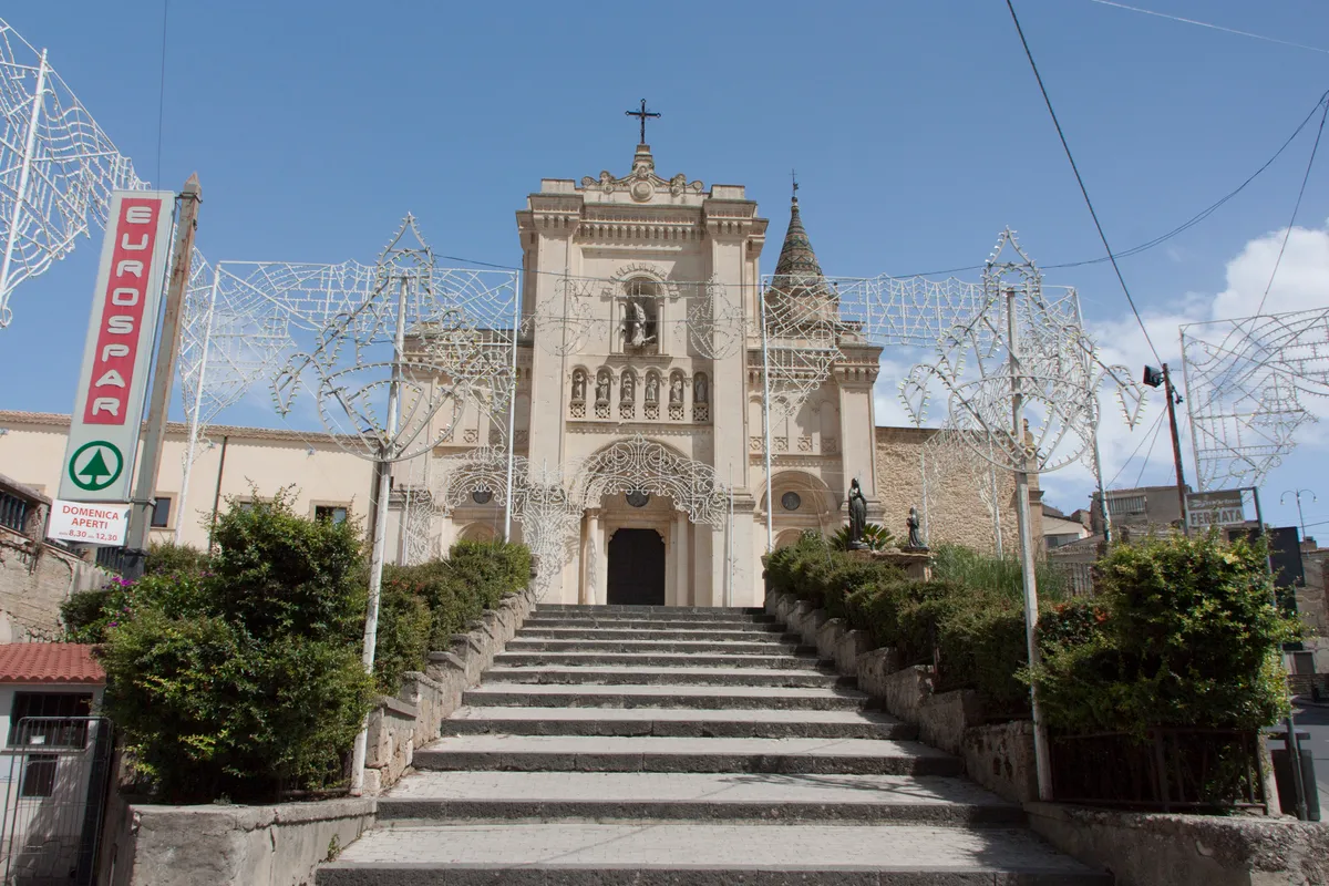 The facade and steps of San Filippo Abbey in Agira, with festival decorations.