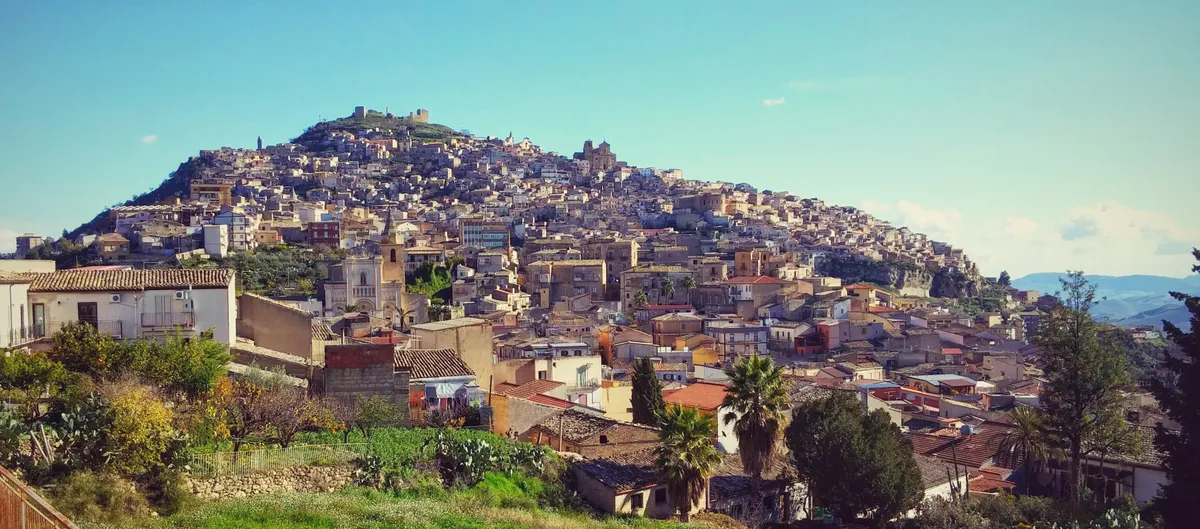 Agira spreading across Monte Teja, with castle ruins on the crest.